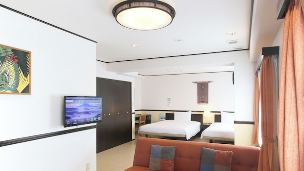 A hotel room with a sofa, two beds, a TV, and a painting on the wall. - Toyoko Inn Okinawa Ishigaki jima (Ishigaki)