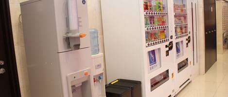 A vending machine with a water dispenser and a beverage vending machine in a hotel corridor.