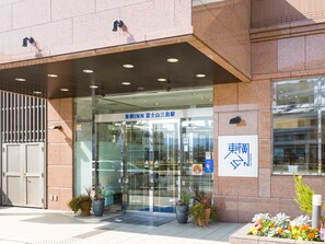 A modern building entrance with a glass door, signage in Japanese, and potted plants. - Toyoko Inn Fujisan Mishima-eki (Mishima)