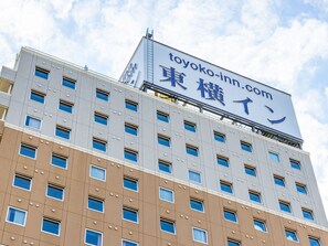 Ein mehrstöckiges Gebäude mit einem Schild für 'toyoko-inn.com' und japanischen Schriftzeichen.