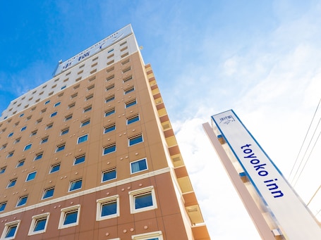 A hotel building with multiple floors, a prominent sign for the Toyota Inn, and a clear blue sky in the background.