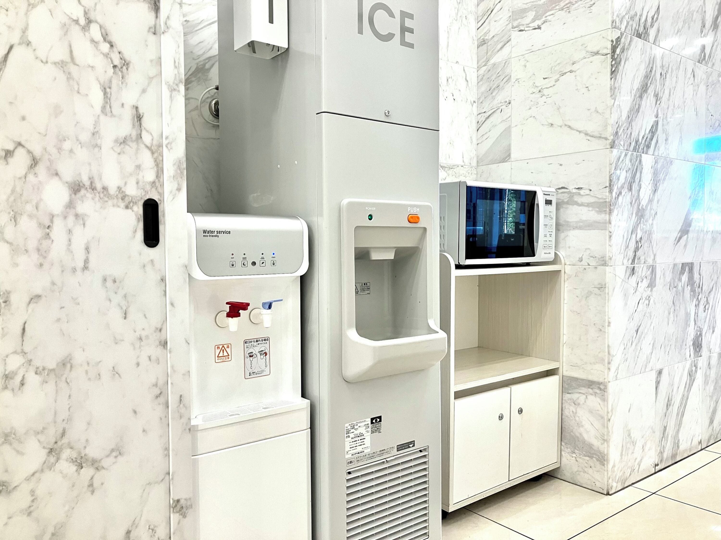 Un dispensador de agua y un microondas en un baño con paredes de mármol.