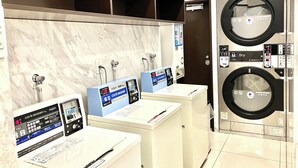 A modern laundry facility with three sinks and two large front-loading washing machines.