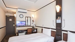 A hotel room with two beds, a desk with a computer, a television, a clock, and a mirror.