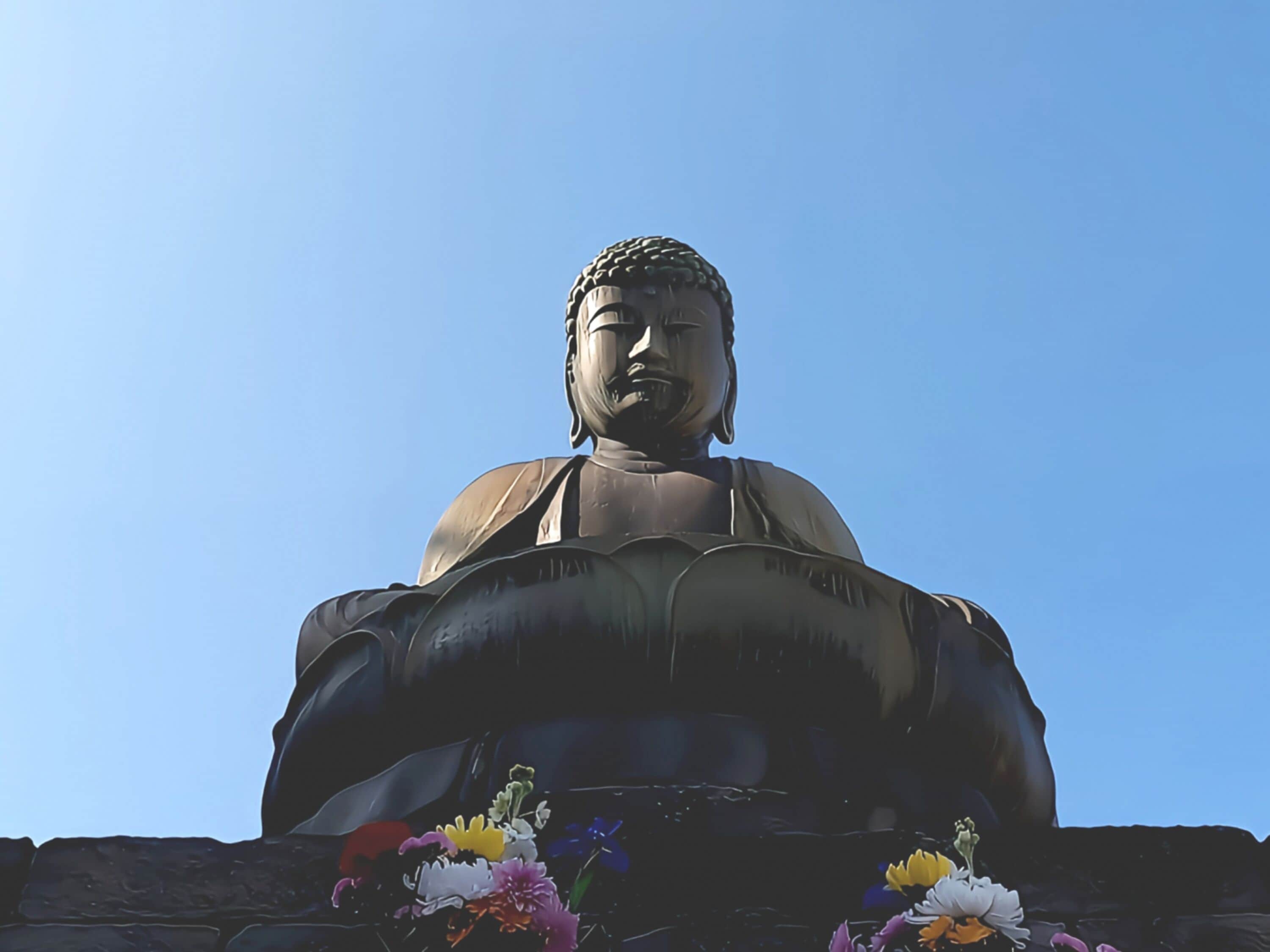 Une grande statue de Bouddha, avec un ciel bleu clair en arrière-plan.