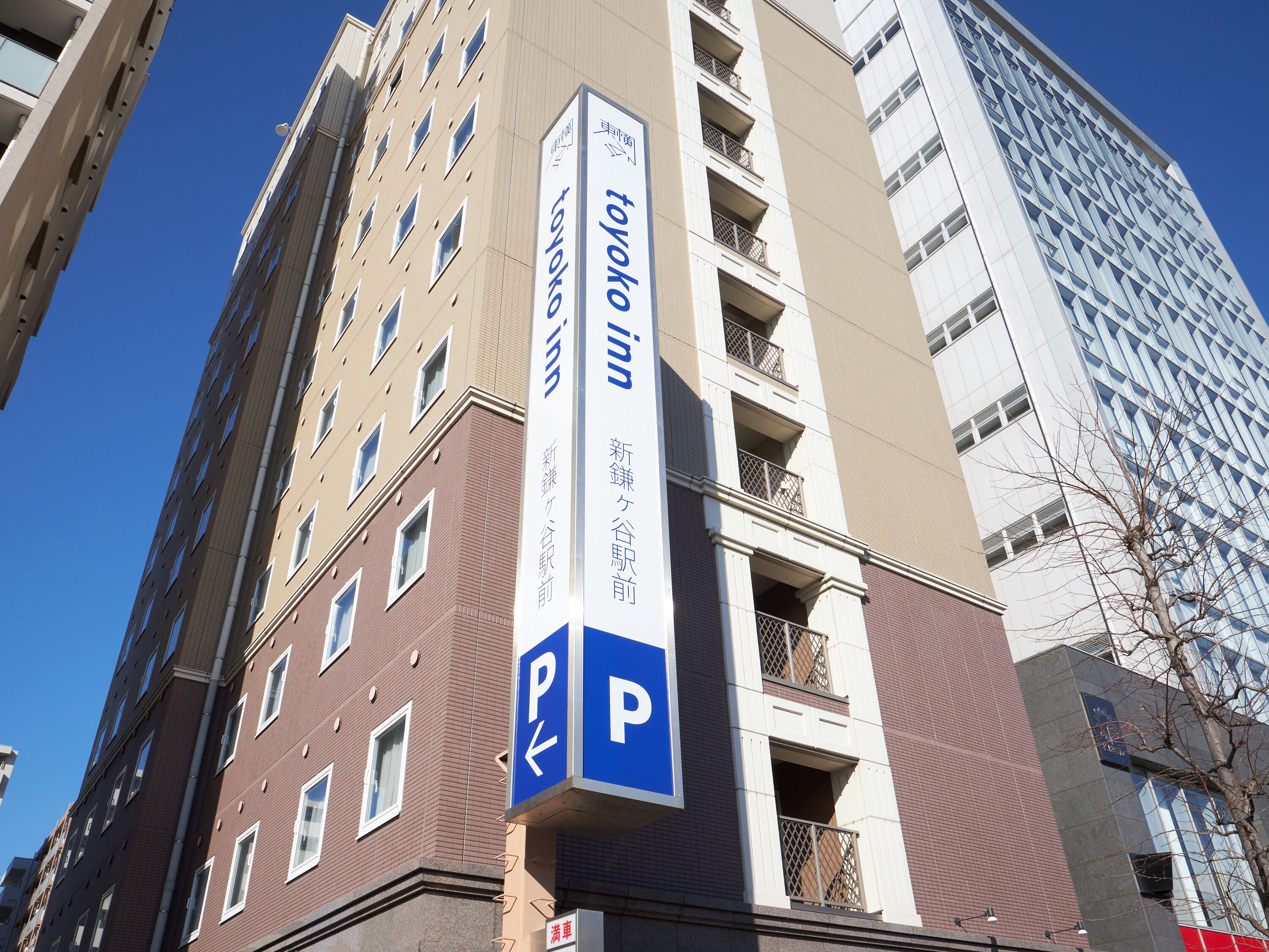 Un edificio de varios pisos con un letrero vertical llamativo que indica un estacionamiento.