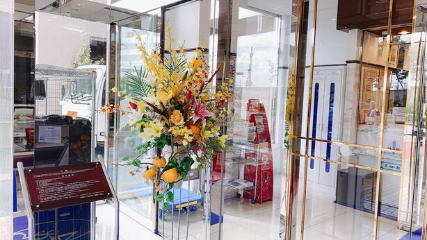 A glass partition with a floral arrangement, a blue cart, and a sign with text.