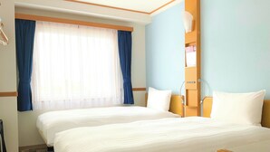 A hotel room with two beds, a window with blue curtains, a bedside table with a lamp, and a wooden headboard. - Toyoko Inn Fukuoka Tenjin (Fukuoka)