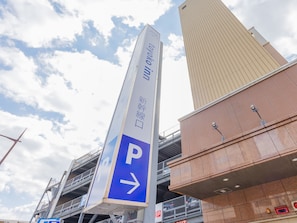 A tall sign with a parking direction arrow and a building with a modern design in the background. - Toyoko Inn Kokura Station Shinkan Line (Kitakyushu)
