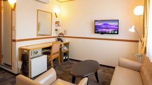 A hotel room with a desk, two chairs, a small table, a TV, and a bed. - Toyoko Inn Kagoshima Chuo Station Nishi (Kagoshima)
