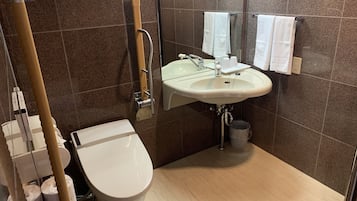 A modern bathroom with a toilet, sink, and handrail.