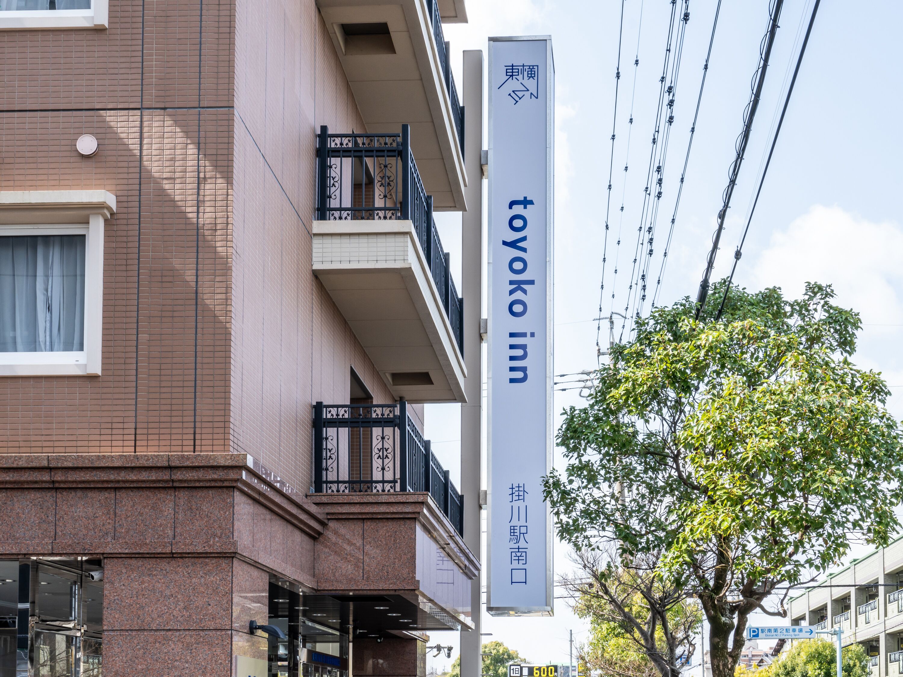 A building with a sign for Toyoko Inn, featuring a modern architectural style with a brick facade and a balcony with black railings.