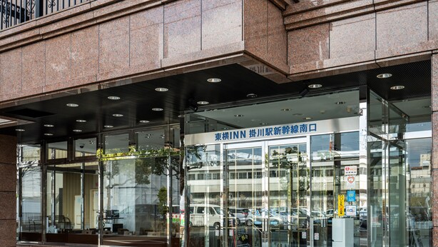 A modern building with a glass entrance, signage for 'INN', and a parking area visible through the windows.