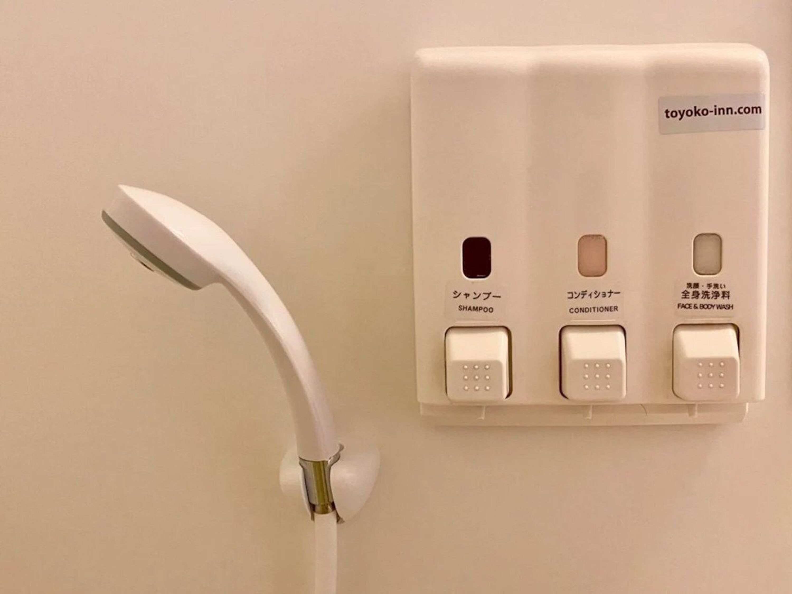 A wall-mounted shower control panel with three buttons labeled for shampoo, conditioner, and face & body wash.
