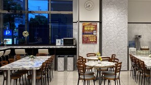 A restaurant with marble-topped tables and chairs, a clock on the wall, and a poster advertising a promotion.