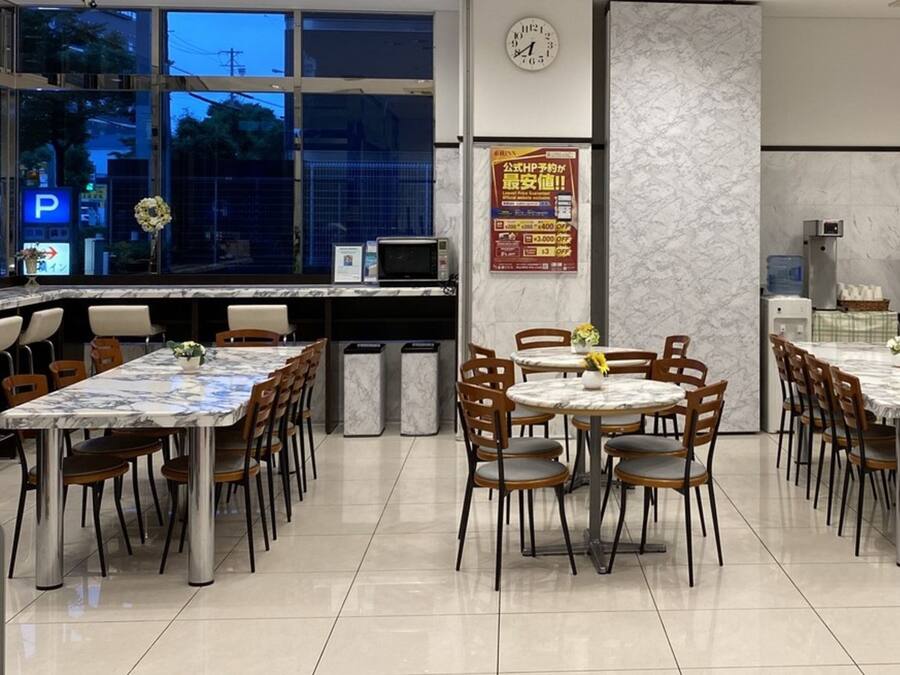 A restaurant with marble-topped tables and chairs, a clock on the wall, and a poster advertising a promotion.
