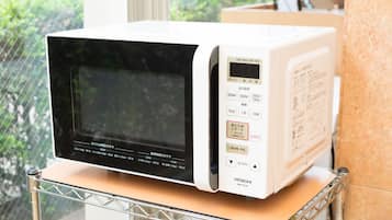 Un four à micro-ondes blanc, doté d’un écran numérique et d’un panneau de commande, posé sur un plan de travail.