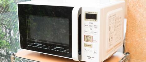Un horno microondas blanco con pantalla digital y panel de control sobre una encimera.
