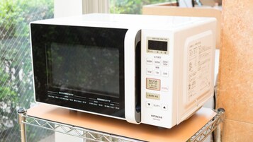 Un horno microondas blanco con pantalla digital y panel de control sobre una encimera.