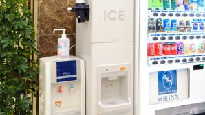 Ein Getränkeautomat mit einer Coca-Cola und einer Handdesinfektionsflasche.