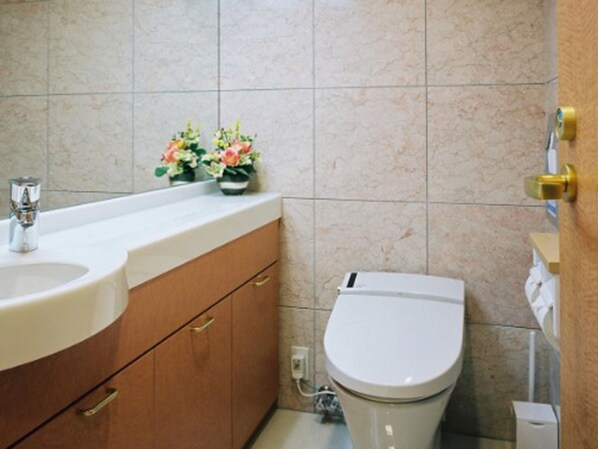 Une salle de bain avec un lavabo blanc, des toilettes et un meuble avec des tiroirs.