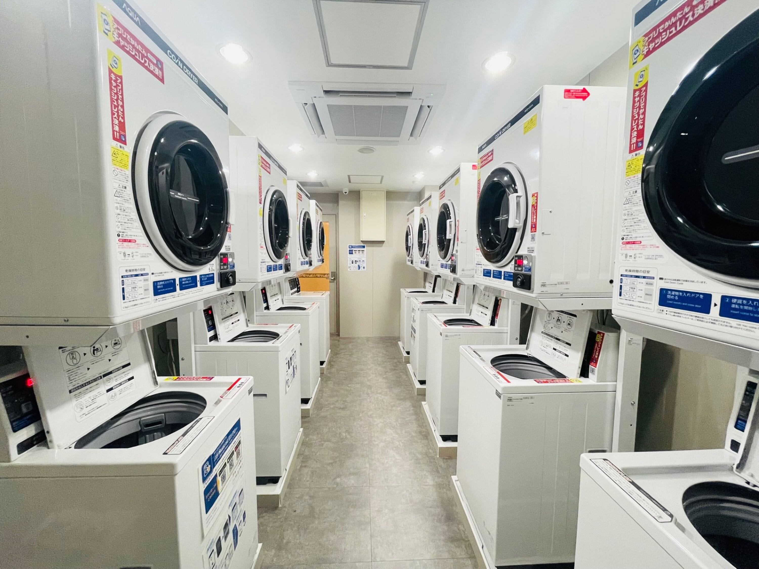 A row of front-loading washing machines in a commercial laundry facility.