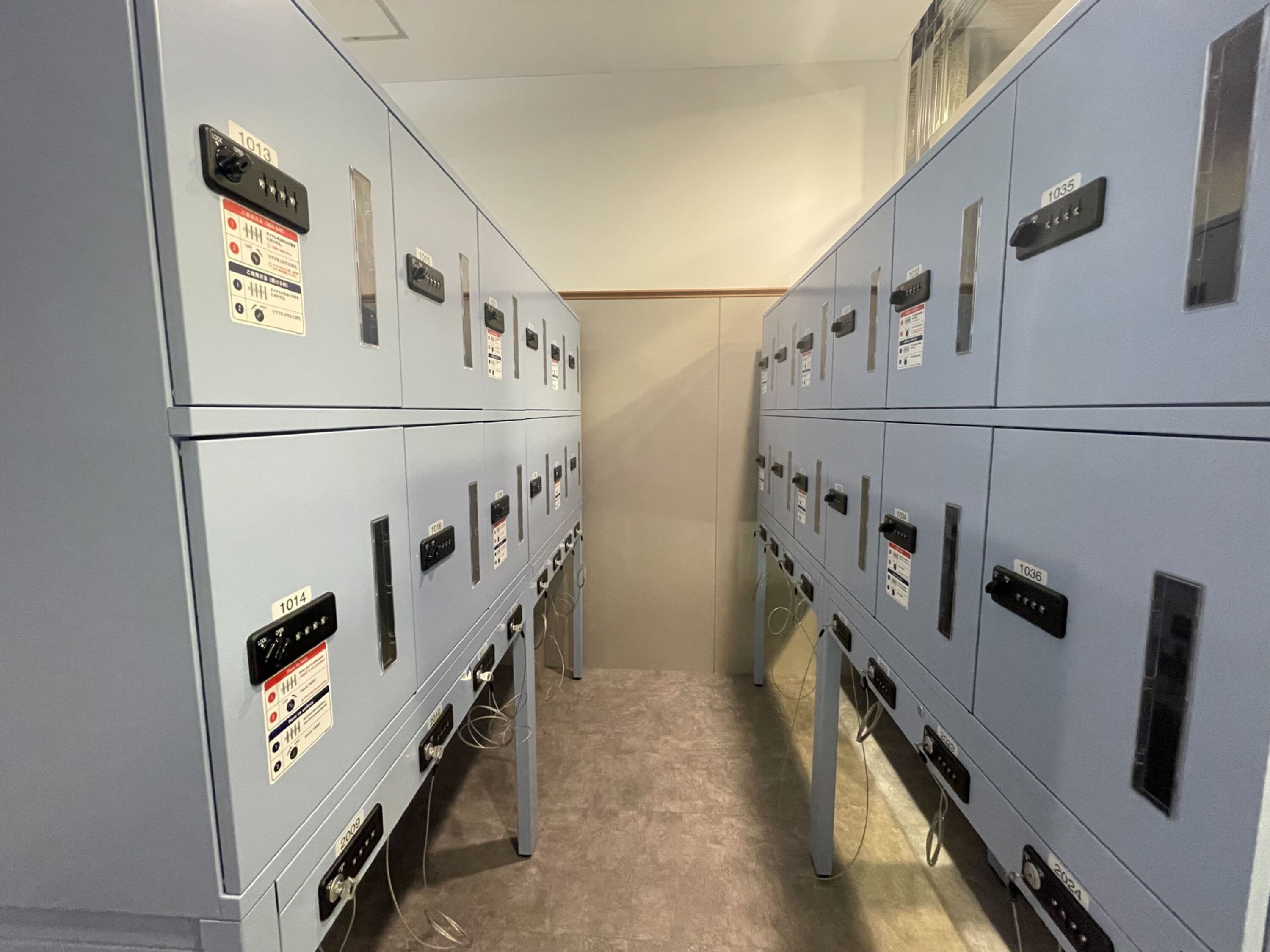 A row of grey electrical panels with labels and switches, arranged in a narrow corridor.