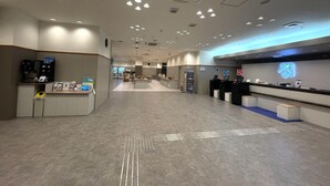 Um hall amplo com balcão de recepção, área de estar e máquina de café.