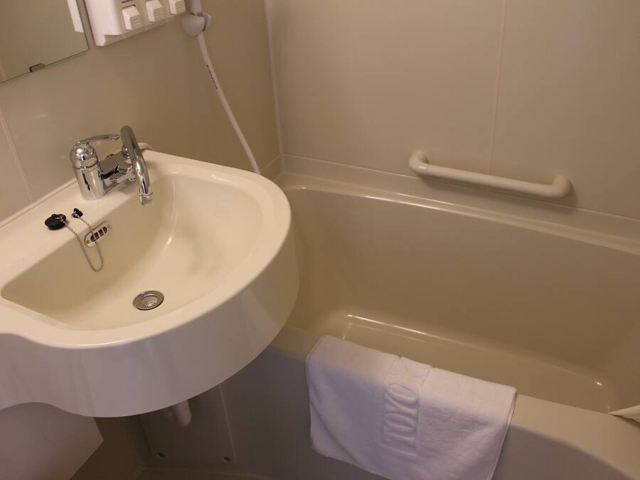 A bathroom with a white sink, a bathtub, and a towel hanging on the wall.
