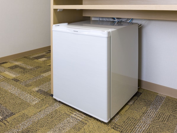 A compact white refrigerator in a corner of a room with a patterned carpet. - Toyoko Inn Tokyo Station Shin Ohashi Mae (Tokyo)