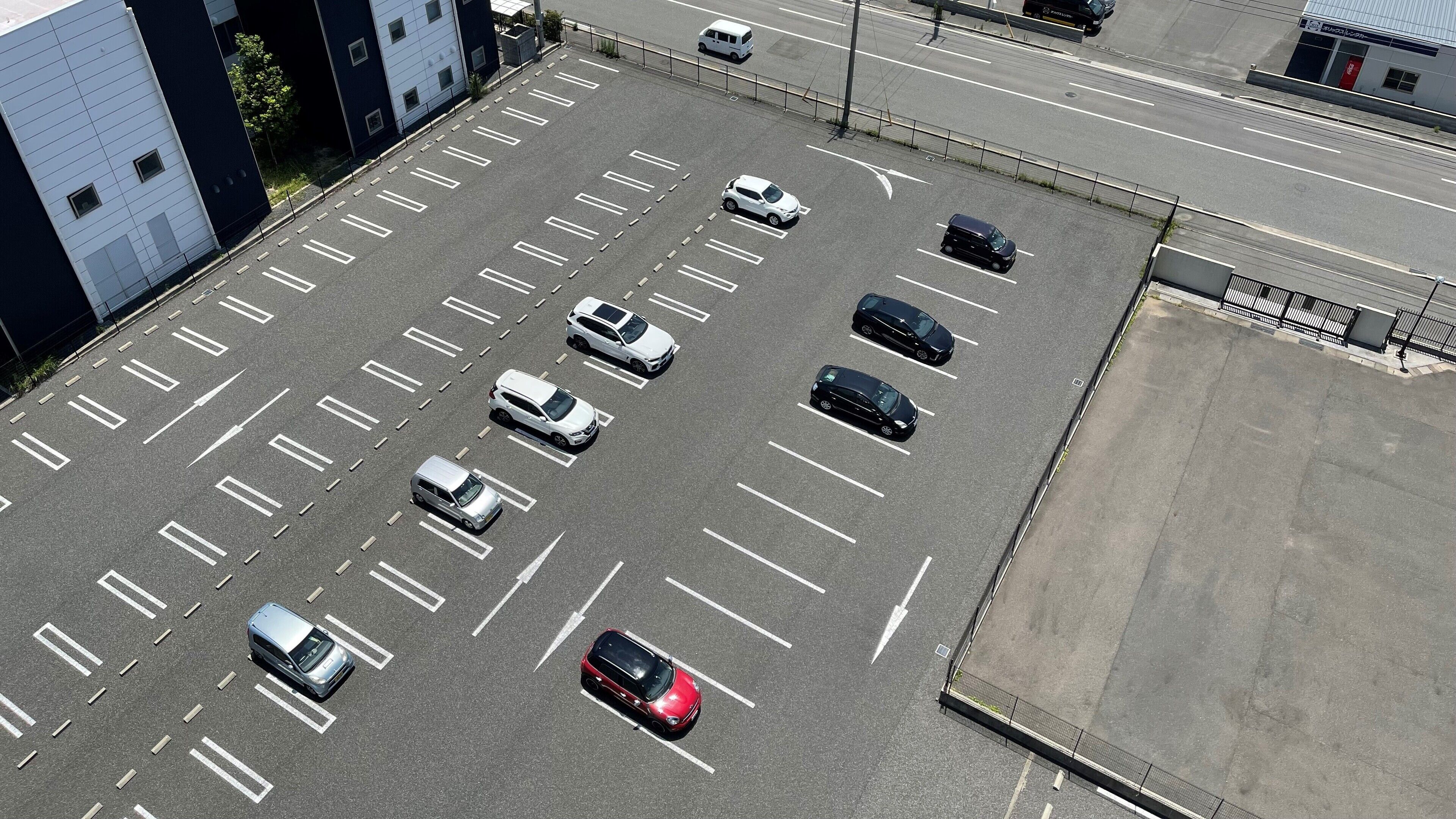 Vista aérea de un estacionamiento con múltiples filas de espacios y algunos automóviles estacionados.
