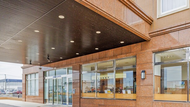Un edificio con una entrada moderna que incluye puertas de cristal y un camino pavimentado con baldosas.