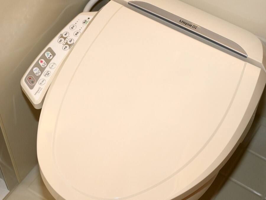 Eine Toilette mit Bedienfeld, das mehrere Knöpfe und einen Markennamen zeigt.