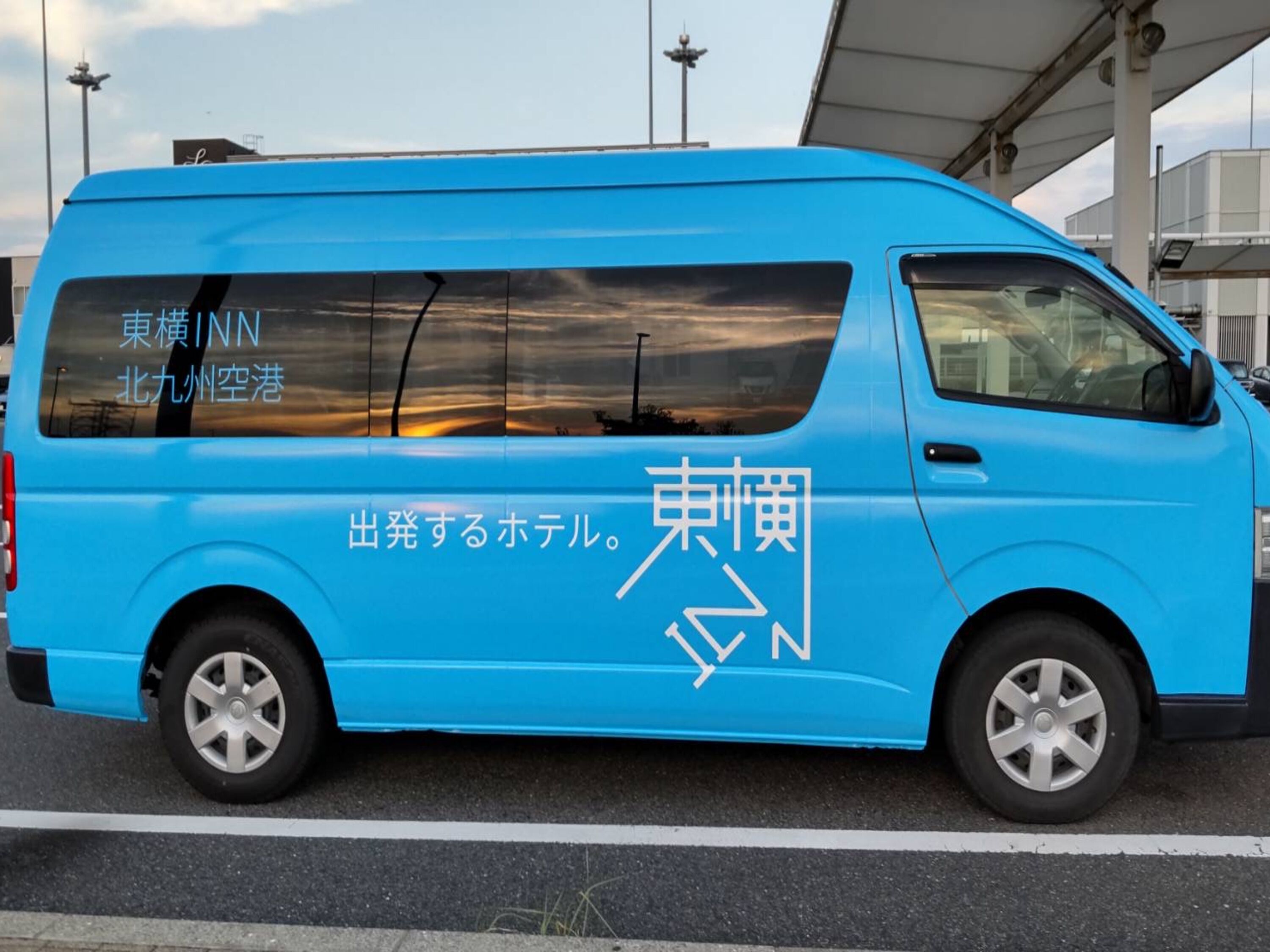 A blue van with Japanese text on the side, parked on a road.