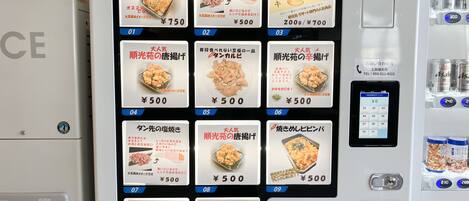 Ein Verkaufsautomat mit verschiedenen Lebensmitteln, deren Preise bei ¥500 liegen, darunter gedämpftes Hähnchen und Reiskuchen.