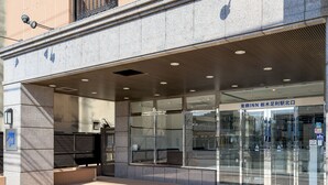 A modern building entrance with glass doors, a ramp for accessibility, and a sign indicating the name of the establishment. - Toyoko Inn Tochigi Ashikaga Station Kita (Ashikaga)