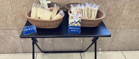 A table with two baskets of bread and two blue signs with Japanese text.