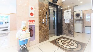 A hotel lobby with a marble floor, a fire extinguisher, a vending machine, and a large mascot statue. - Toyoko Inn Kiryu Station Minami (Kiryu)