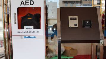 Un dispositivo médico etiquetado como DEA, un desfibrilador portátil y un panel de control sobre una mesa.