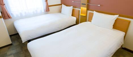 Una habitación de hotel con dos camas individuales, una mesita de noche pequeña, cortinas en una ventana y una lámpara de pared.