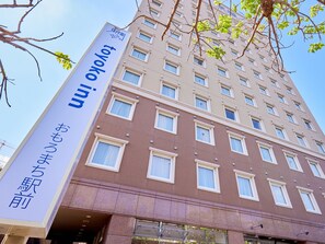 Um edifício de hotel com vários andares, janelas amplas e uma placa indicando ser um hotel.