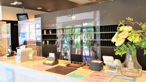 A reception desk with a glass partition, a clock, and a vase with flowers.