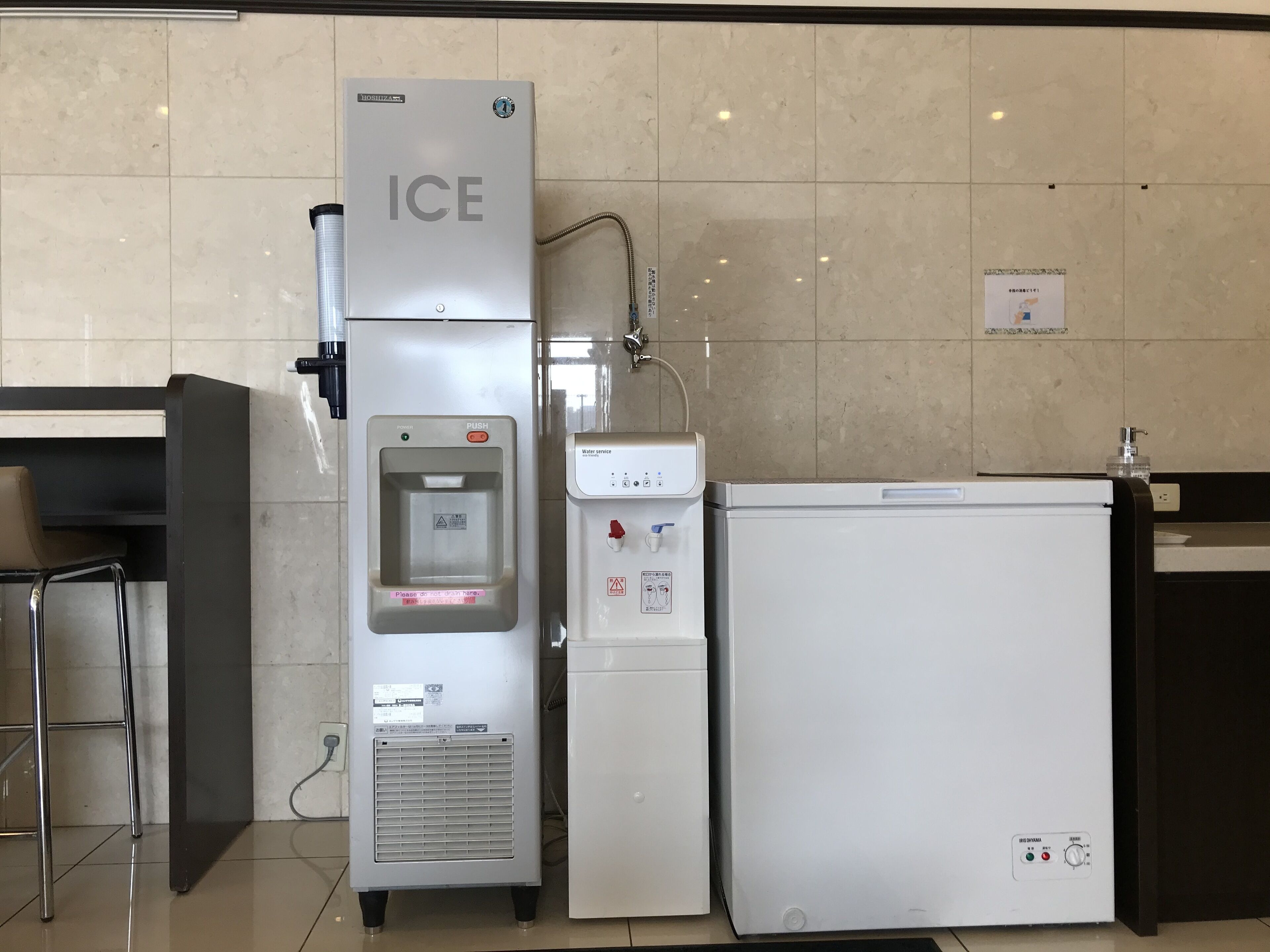 Dispensador de água e frigorífico em um ambiente de hotel.