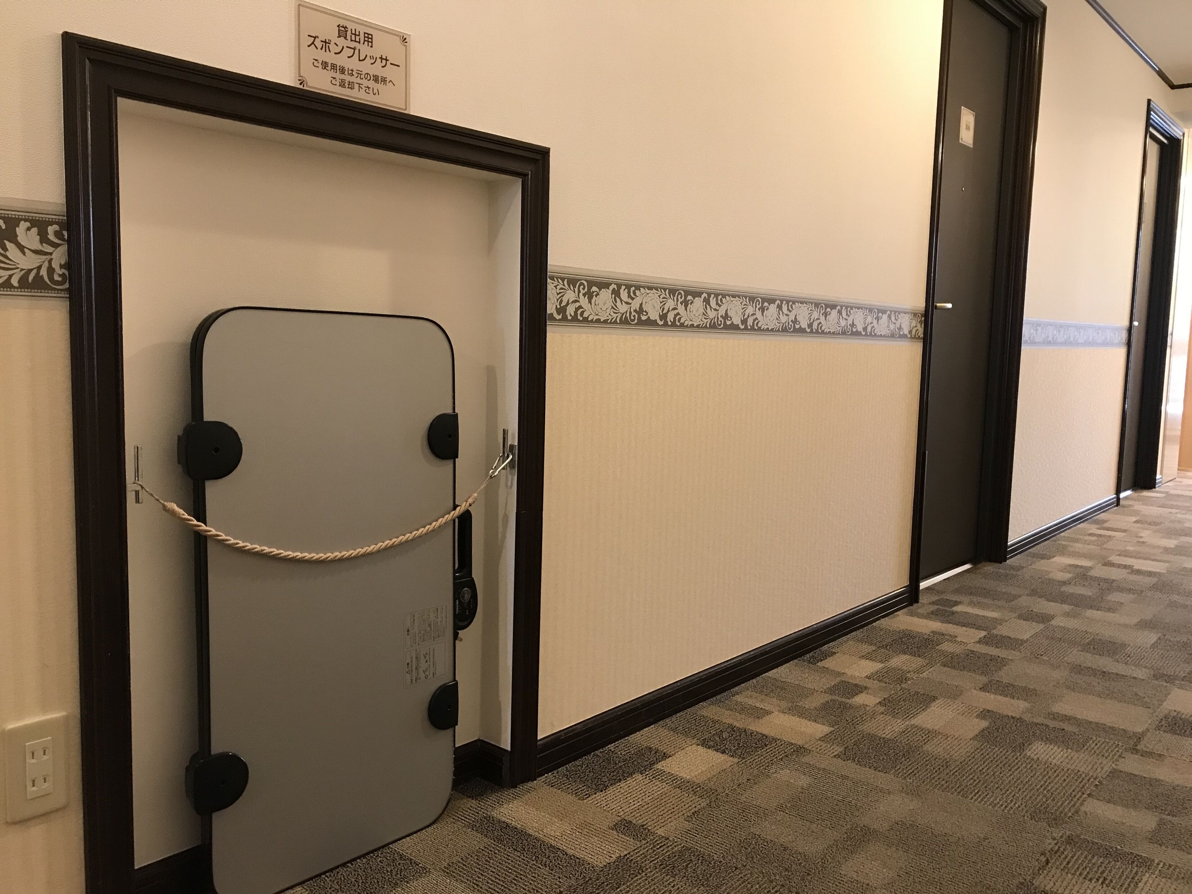 Un pasillo con una puerta que tiene un letrero indicando que es una habitación de alquiler.