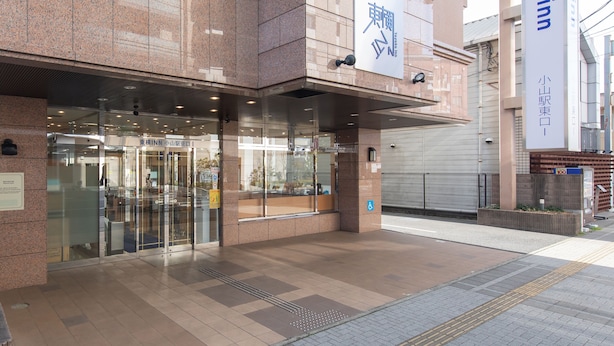 Un bâtiment moderne avec une enseigne bien visible pour la chaîne d’hôtels Toyoko Inn.
