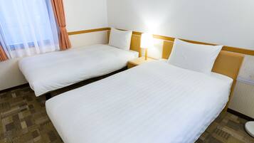 A hotel room with two single beds, a nightstand with a lamp, and a window with curtains.