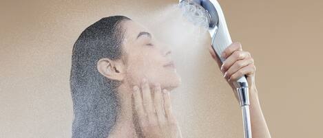 Una persona usando un cabezal de ducha de mano, con agua salpicando a su alrededor.