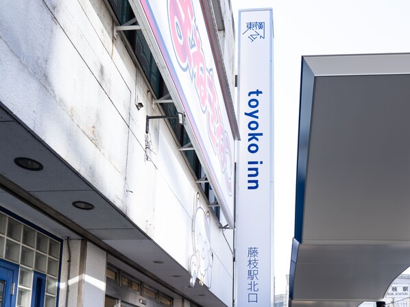 Un edificio con un letrero de 'Toyoko Inn' y un cartel que indica 'Estación Tsubasa' cerca.