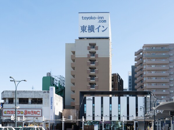 Um edifício de vários andares com uma placa de destaque para 'toyoko-inn.com' e caracteres japoneses.