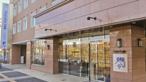 A hotel entrance with a glass facade, signage in multiple languages, and a clear pathway leading to the entrance. - Toyoko Inn Moriya Ekimae (Moriya)